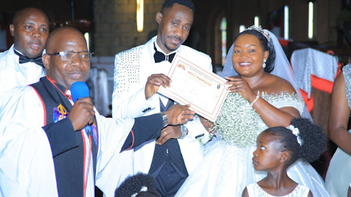 The priest presents the couple with their marriage certificate The priest presents the couple with their marriage certificate